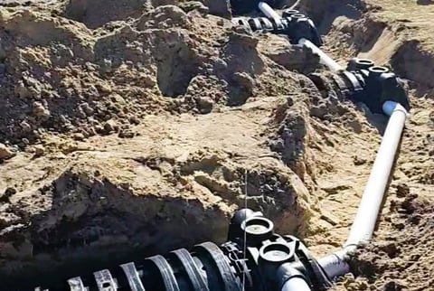 Underground drainage pipes with corrugated black tubing installed in excavated soil during construction work