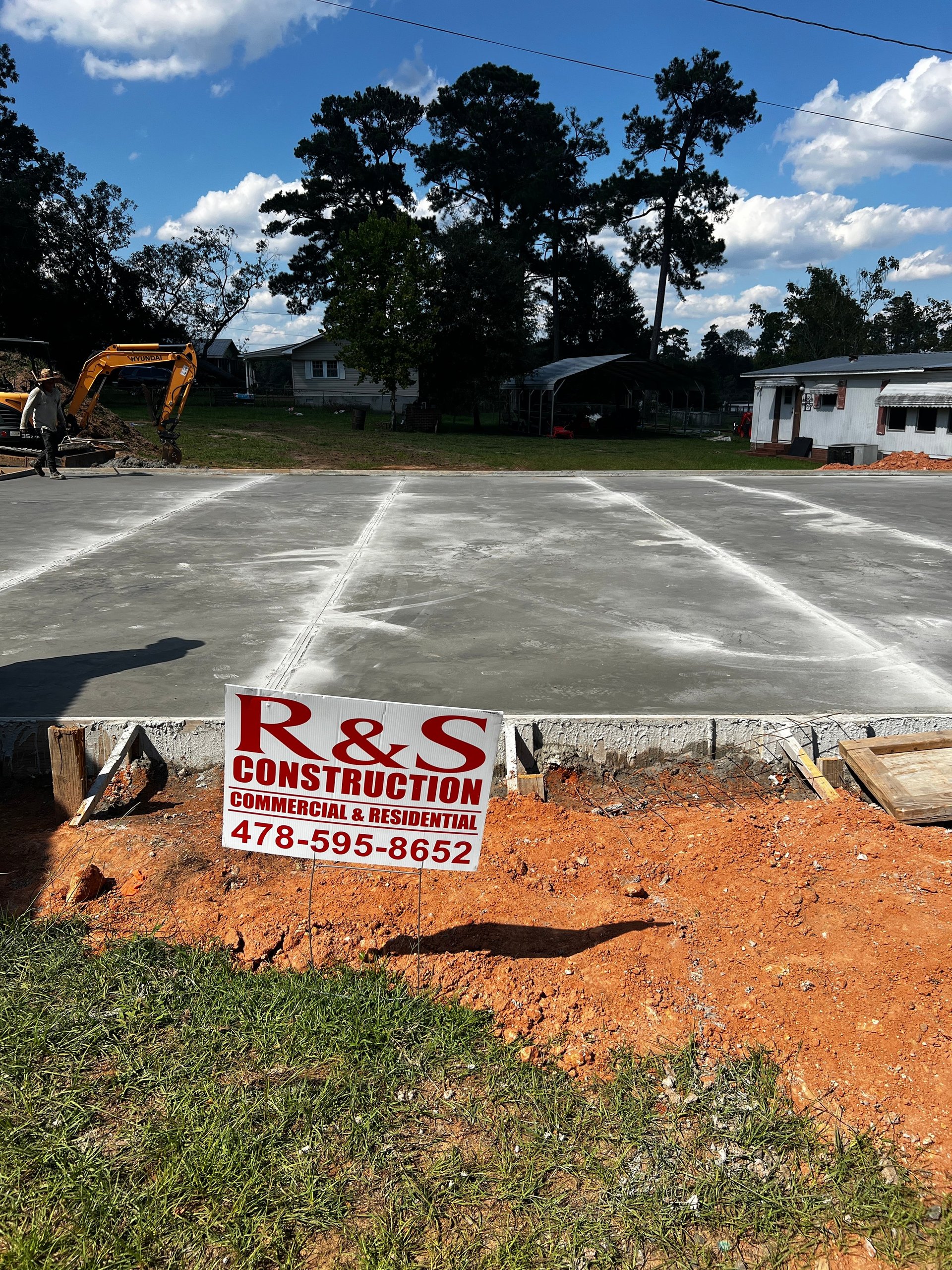 R&S Construction site with sign, concrete foundation, and equipment