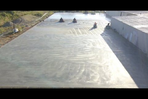 Aerial view of a large concrete roof being troweled and finished by workers during construction or renovation